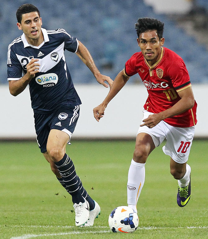 Teerasil Dangda of Muangthong United (right) runs past a defender of Melbourne Victory during their AFC Champions League playoff match at Skilled Stadium in Melbourne on February 15, 2014