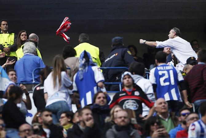 An Atletico Madrid fan, right, throws his team's scarf to Deportivo Coruna supporters during their Spanish first division soccer match