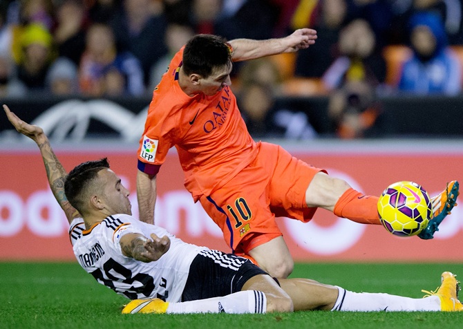 Lionel Messi, right, of FC Barcelona is tackled by Nicolas Otamendi of Valencia