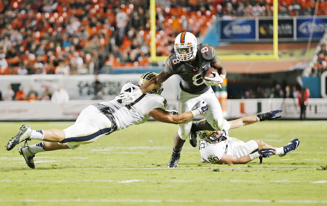 Duke Johnson #8 of the Miami Hurricanes stiff arms Matt Galambos #47 of the Pittsburgh Panthers to score a third quarter touchdown