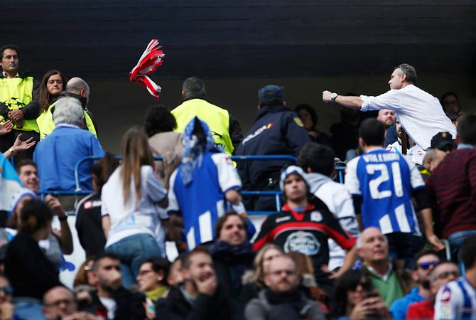 An Atletico Madrid fan (right) flings his team's scarf to Deportivo Coruna supporters during their La Liga match