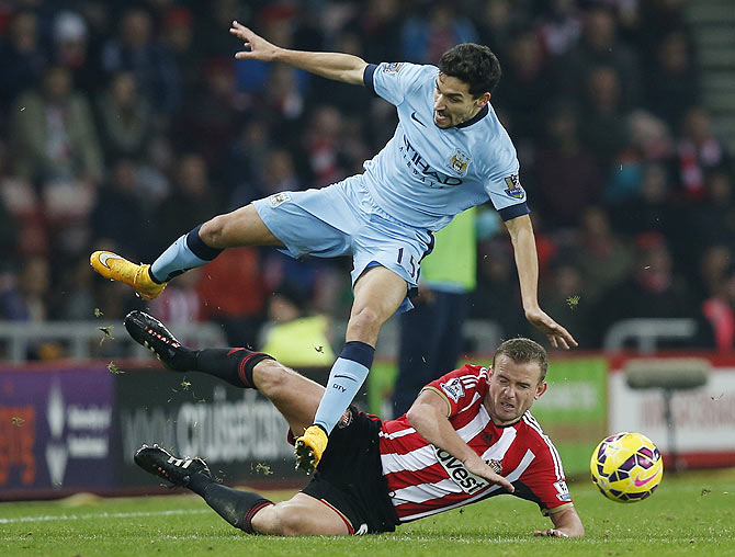 Sunderland's Lee Cattermole challenges Manchester City's Jesus Navas (top)