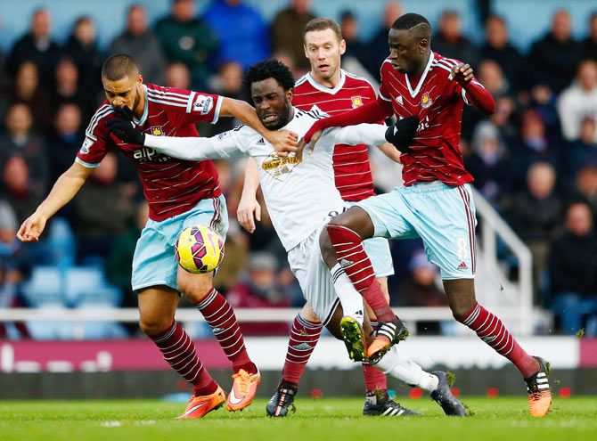 Wilfried Bony of Swansea City is closed down by West Ham's Winston Reid (left) Kevin Nolan and Cheikhou Kouyate (right) during their match on Sunday
