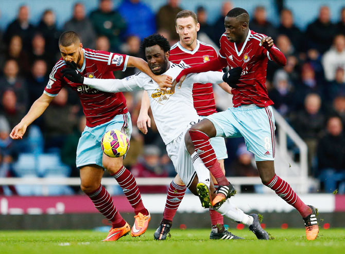 Wilfried Bony of Swansea City is closed down by West Ham's Winston Reid (left) Kevin Nolan and Cheikhou Kouyate (right)