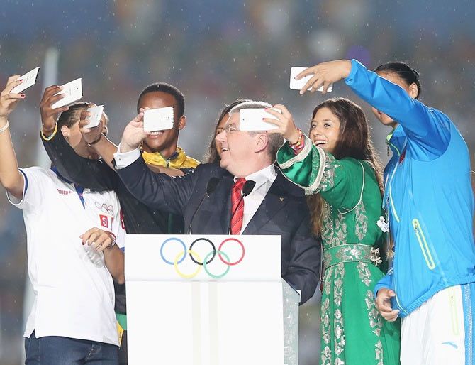 Participants take pictures with International Olympic Committee president Thomas Bach, center, after he delivered a speech