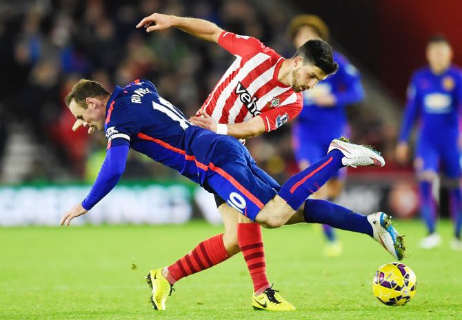 Shane Long of Southampton challenges Wayne Rooney of Manchester United during their match on Monday