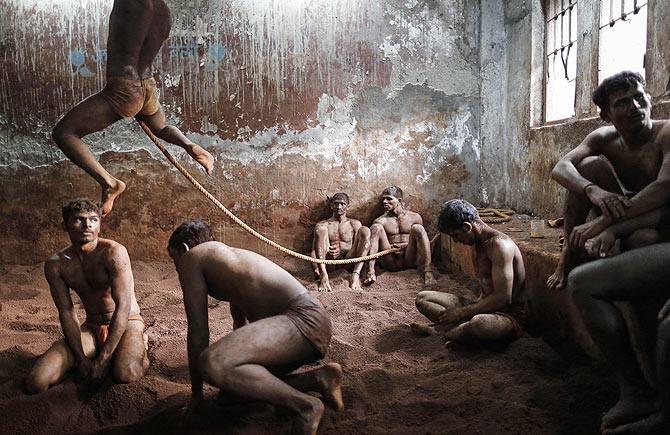 Wrestlers practise as others rest in the mud at a traditional Indian wrestling centre called Akhaara in Mumbai March 4, 2014. Kushti (mud wrestling) is a traditional sport in India but more and more young athletes are now training to wrestle on mats instead of mud to gain access to top international competitions like the Olympic Games or the Commonwealth Games.