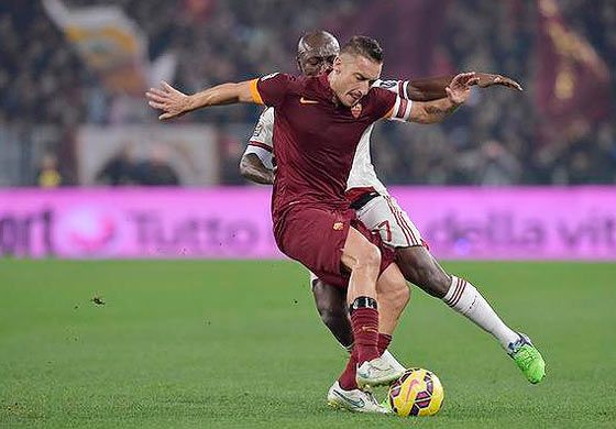 Francesco Totti is challenged by an AC Milan player during their match on Sunday