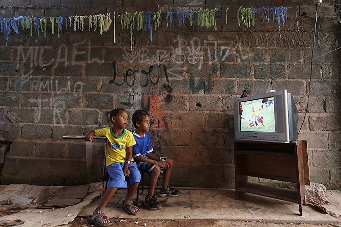 Boys watch a screening of the 2014 World Cup Group A match between Brazil and Mexico, at the slum of Varjao on the outskirts of Brasilia in Brazil on June 17