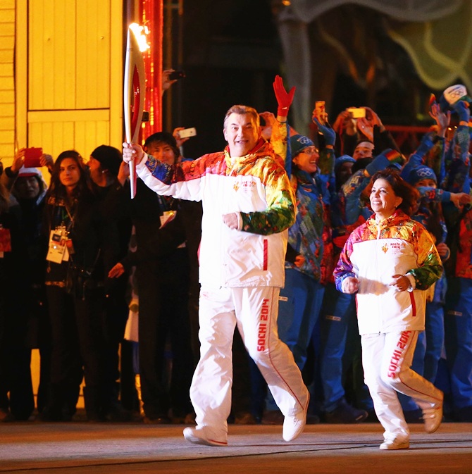 Irina Rodnina and Vladislav Tretyak approach the the Olympic cauldron as they prepare to light it