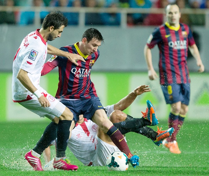 Lionel Messi, right, of FC Barcelona competes for the ball with Nicolas Pareja,left, of Sevilla FC