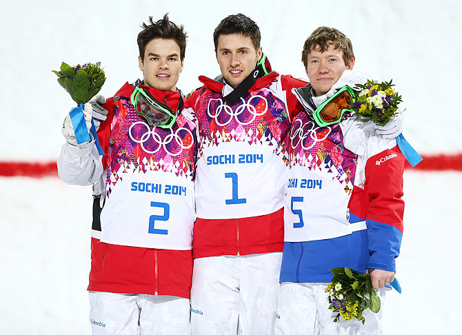 (Left-Right) Silver medalist Mikael Kingsbury of Canada, gold medalist Alex Bilodeau of Canada and Alexandr Smyshlyaev of Russia celebrate on the podium during the flower ceremony after the Men's Moguls final of the Sochi 2014 Winter Olympics at Rosa Khutor Extreme Park on Monday