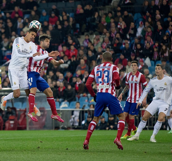 Raphael Varane of Real Madrid CF wins the header after Diego Ribas of Atletico de Madrid.