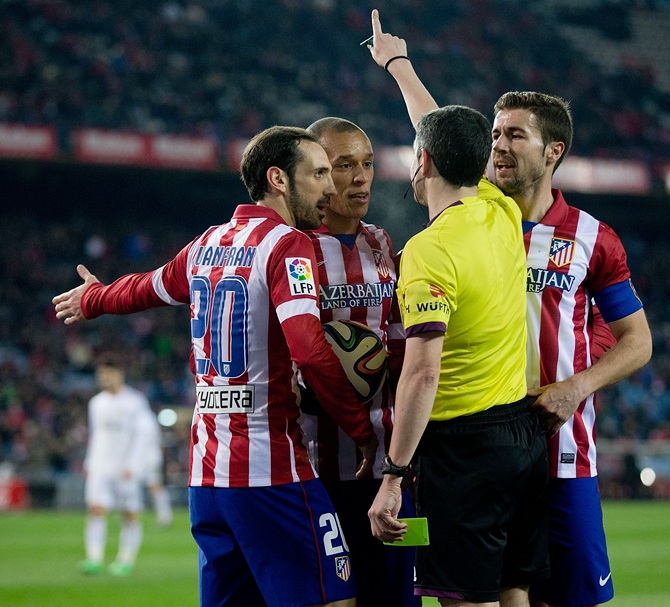 Joao Miranda, second left of Atletico de Madrid and his teammates Juan Francisco Torres alias Juanfran, left, and Gabi Fernandez argue with referee Undiano Mallenco.