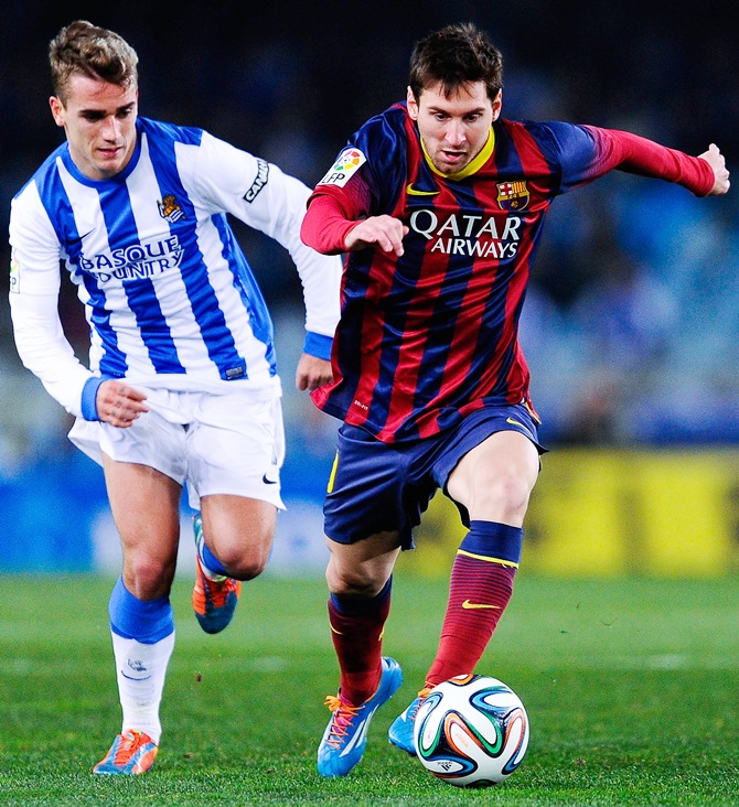 Lionel Messi of FC Barcelona runs with the ball chased by Antoine Griezmann of Real Sociedad.