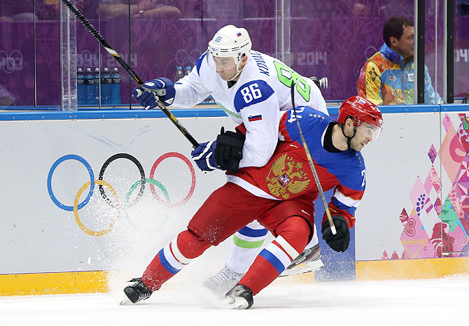 Alexander Popov #24 of Russia skates against Sabahudin Kovacevic #86 of Slovenia in the third period during the Men's Ice Hockey Preliminary Round Group A game at Bolshoy Ice Dome in Sochi on Thursday