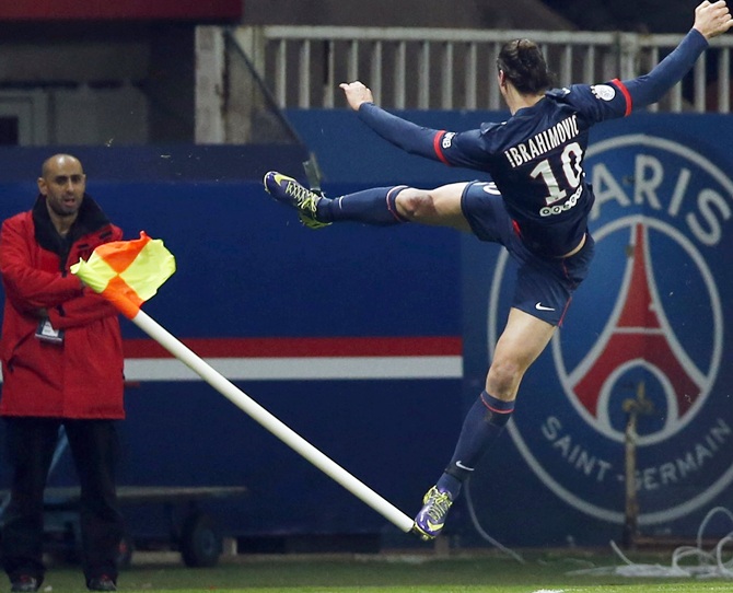 Paris St Germain's Zlatan Ibrahimovic,right, jumps and kicks a corner flag as he celebrates scoring.