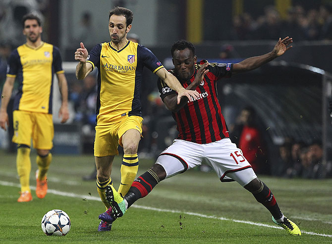 Juanfran of Atletico Madrid is challenged by Michael Essien of AC Milan during their Champions League match on Wednesday