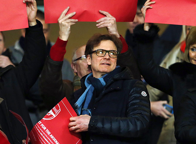 British actor Colin Firth holds a placard during the Champions League round of 16 first leg soccer match between Arsenal and Bayern Munich at the Emirates Stadium in London on Wednesday