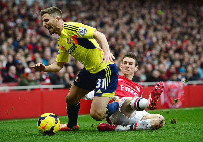Fabio Borini of Sunderland is tackled by Laurent Koscielny of Arsenal during their English  Premier League match at Emirates Stadium on Saturday