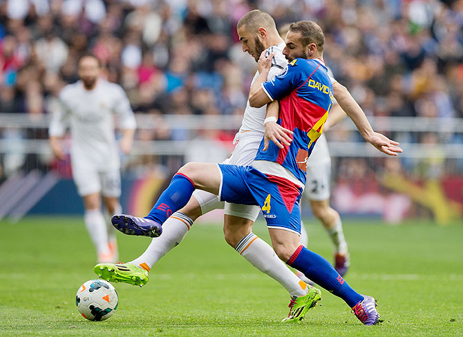 Karim Benzema of Real Madrid CF (left) competes for the ball with David Rodriguez Lomban of Elche FC during their La Liga match on Saturday