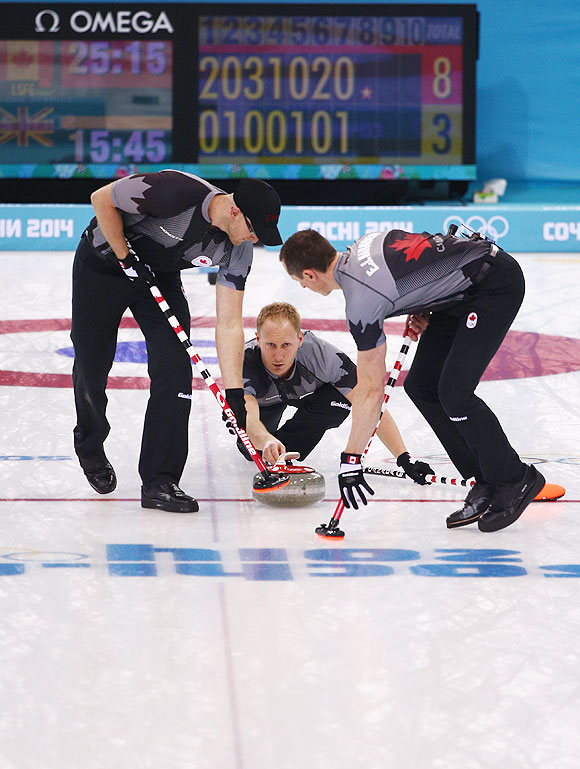 Brad Jacobs (centre) of Canada plays the final stone during the Men's Gold Medal match between Canada and Great Britain