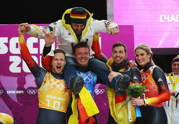 (From left) Gold medalists Tobias Arlt, Felix Loch, Tobias Wendl and Natalie Geisenberger of Germany lift   their coach Georg Hackl in celebration during the flower ceremony for the the Luge Relay at Sliding Center Sanki in Sochi on Thursday.