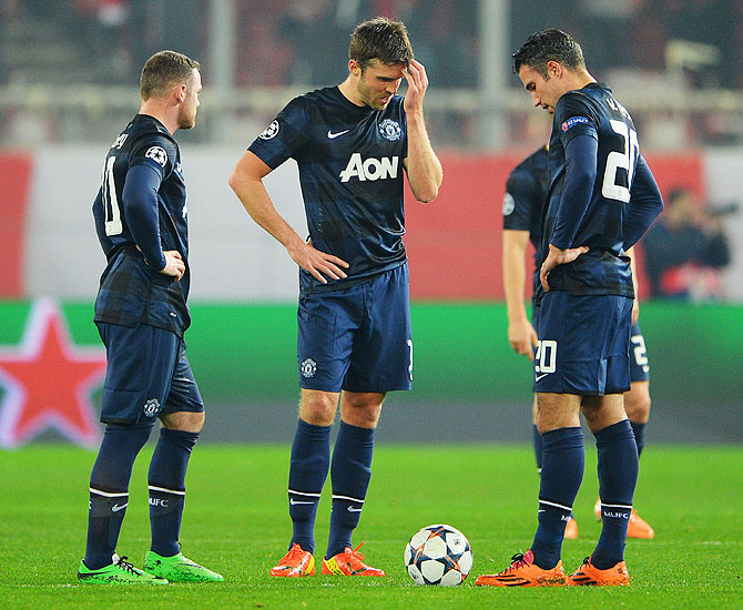 Wayne Rooney, Michael Carrick and Robin van Persie of Manchester United react as they restart the game after conceding the first goal during their Champions League Round of 16 first leg match against Olympiacos FC at Karaiskakis Stadium in Piraeus, Greece, on Tuesday
