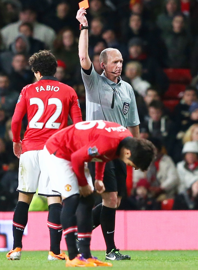 Referee Michael Dean shows a red card to Fabio of Manchester United