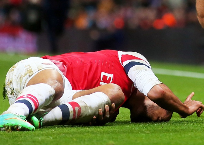 Theo Walcott of Arsenal lies injured on the pitch