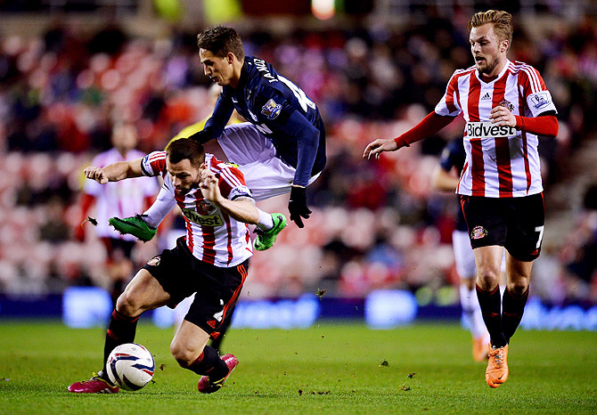 Adnan Januzaj of Manchester United is challenged by Phil Bardsley of Sunderland as Sebastian Larsson of Sunderland (right) looks on during their League Cup semi-final, first leg match on Tuesday
