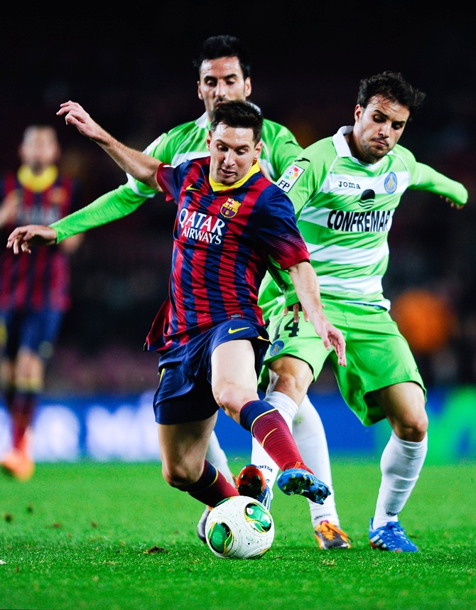 Lionel Messi of FC Barcelona duels for the ball with Juan Rodriguez (left) and Pedro Leon of Getafe CF