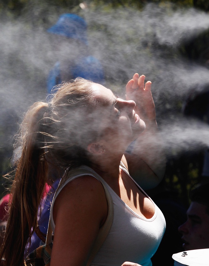 A fan cools down in front of a mister during day one of the 2014 Australian Open at Melbourne Park