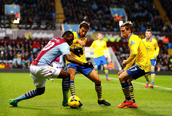 Christian Benteke of Aston Villa (left) is closed down by Mathieu Flamini and Per Mertesacker of Arsenal during their English Premier League match on Monday