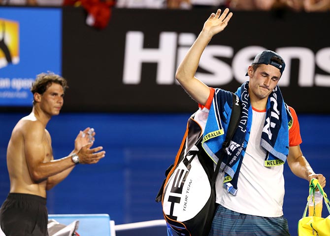 Bernard Tomic (right) leaves the court as Rafael Nadal claps