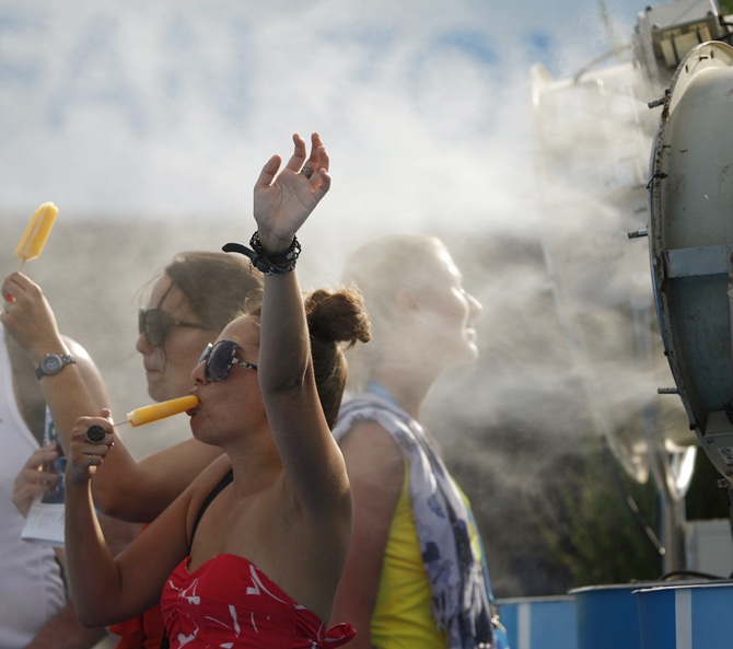 Spectators cool off with popsicles in front of a misting fan at the Australian Open in Melbourne