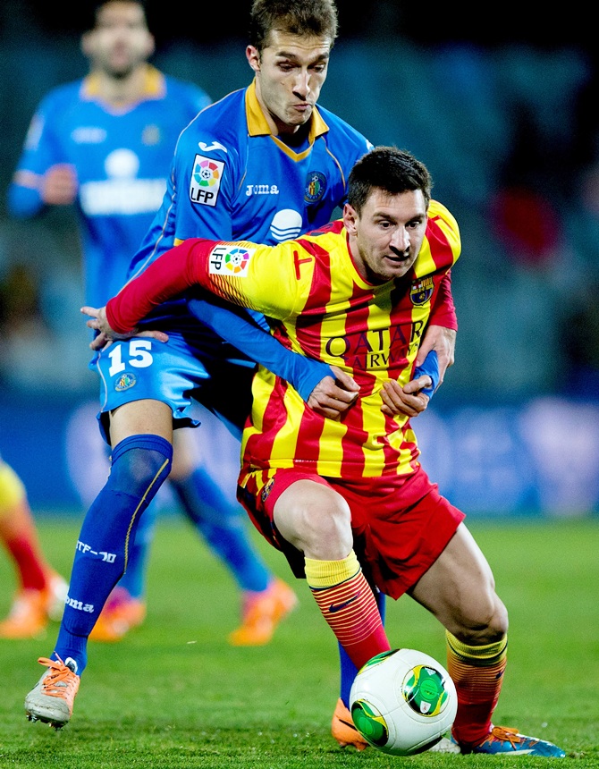 Lionel Messi of FC Barcelona competes for the ball with Rafael Lopez of Getafe