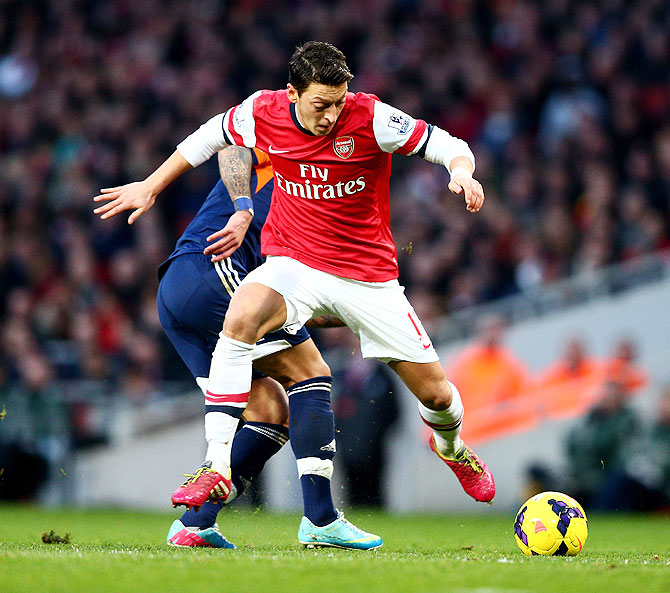 Mesut Ozil of Arsenal is challenged by Ashkan Dejagah of Fulham during their match on Saturday