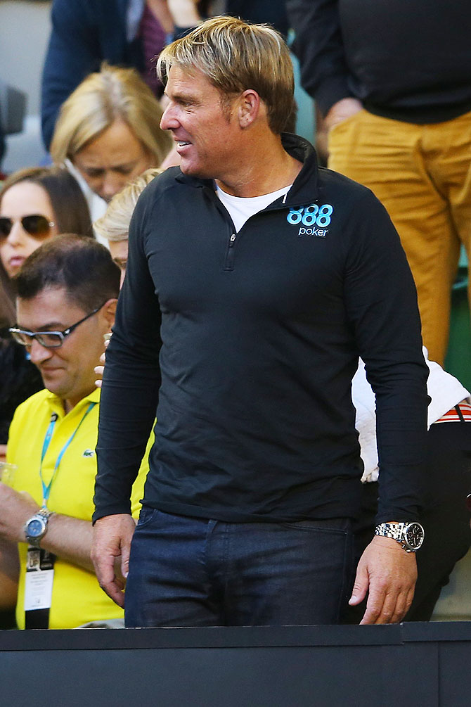 Former Australian cricketer Shane Warne watches the quarter-final between Roger Federer and Andy Murray