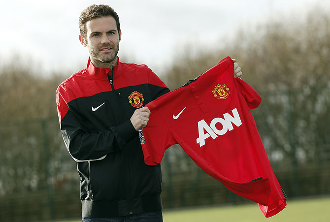 Manchester United's new signing Juan Mata holds a club shirt during a photocall at the club's Carrington training complex in Manchester on Monday