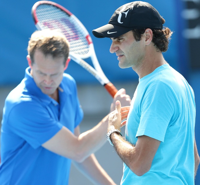 Roger Federer of Switzerland trains in a practice session as his coach, Stefan Edberg watches