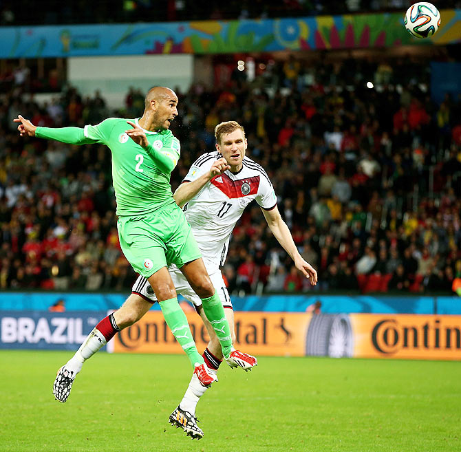 Madjid Bougherra of Algeria and Per Mertesacker of Germany are involved in an aerial challenge during their match on Monday