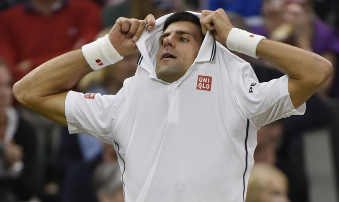 Novak Djokovic of Serbia takes off his shirt during a break