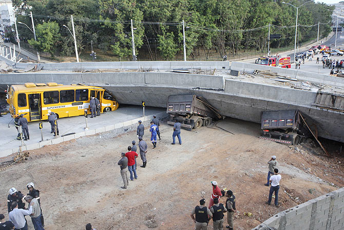 Rescue workers try to reach vehicles trapped underneath a bridge that collapsed while under construction in Belo Horizonte on Thursday