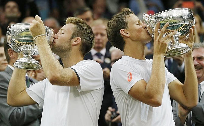 Vasek Pospisil of Canada and Jack Sock of the U.S. (L) kiss their winners trophies after defeating Bob Bryan of the U.S. and Mike Bryan of the U.S. in their men's doubles final tennis match at the Wimbledon Tennis Championships, in London on Saturday