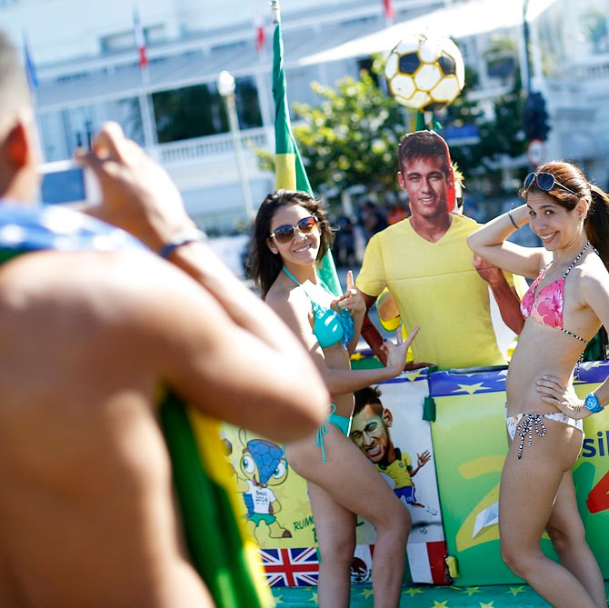 Tourists pose with a Brazilian soccer fan (C, obscured) holding an image of Neymar, inside her car which has been decorated to celebrate the 2014 World Cup, in Copacabana beach in Rio de Janeiro