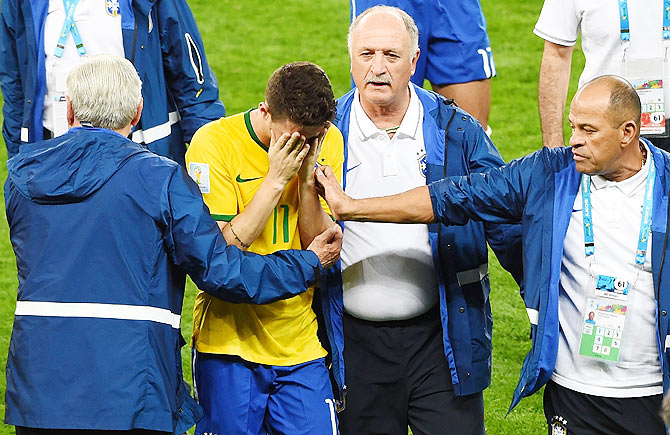 Head coach Luiz Felipe Scolari of Brazil and staff console Oscar after a 7-1 defeat to Germany on Tuesday