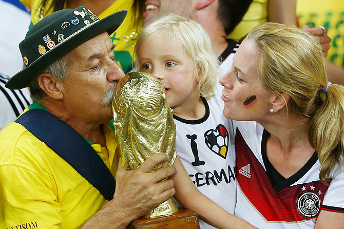 A Brazil fan and young Germany fan kiss a replica of the World Cup trophy after Germany's 7-1 win on Tuesday
