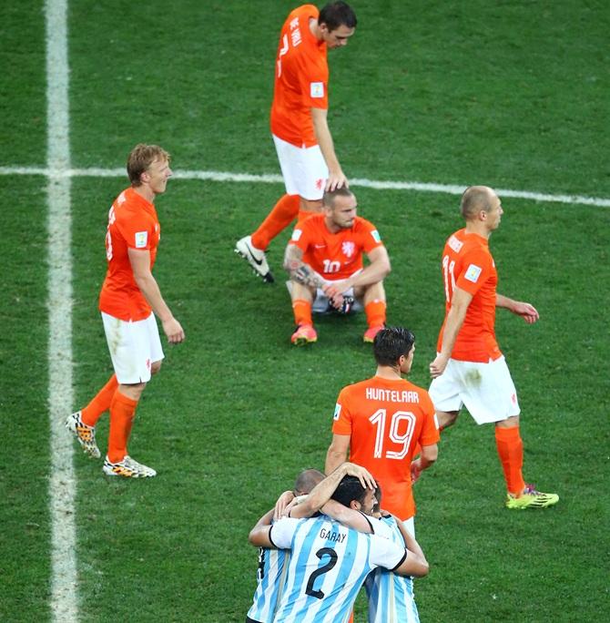 Javier Mascherano, Ezequiel Garay and Lucas Biglia of Argentina celebrate after   defeating the Netherlands in a penalty shootout as Dirk Kuyt, Stefan de Vrij,   Wesley Sneijder, Klaas-Jan Huntelaar and Arjen Robben of the Netherlands look on