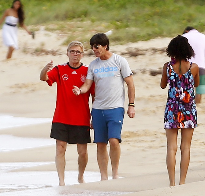 Germany's coach Joachim Loew listens to head match analyst Urs Siegenthaler, left, as they walk on the beach in front of their base camp Campo Bahia, in the village of Santo Andre north of Porto Seguro